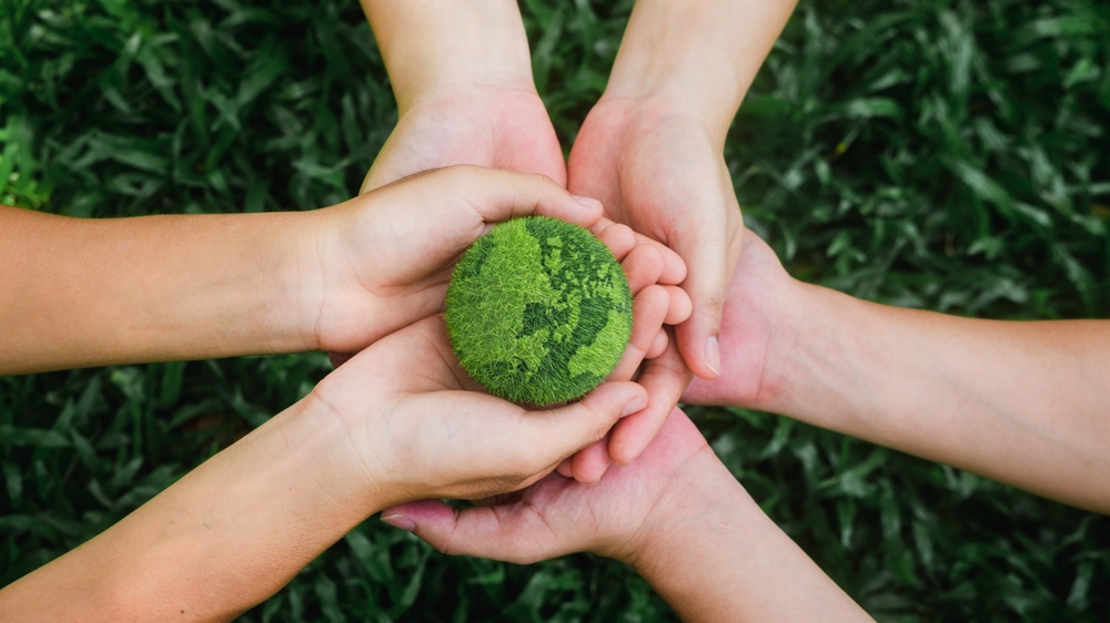 Hands holding a green ball that looks like the earth.