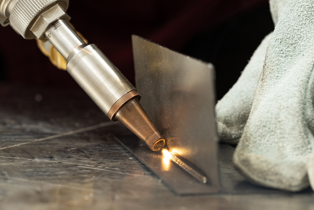 Close-up of handheld laser welding on metal, producing a visible fume plume
